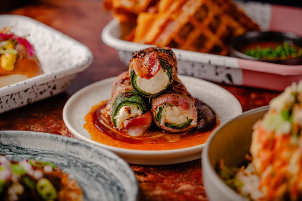 RC3-January25-FullAlbum-76 Charred and pickled jalapeños, stuffed with burnt ends, cream cheese, and herbs, wrapped in applewood-smoked bacon and topped with marshmallow BBQ sauce and Alabama white sauce.