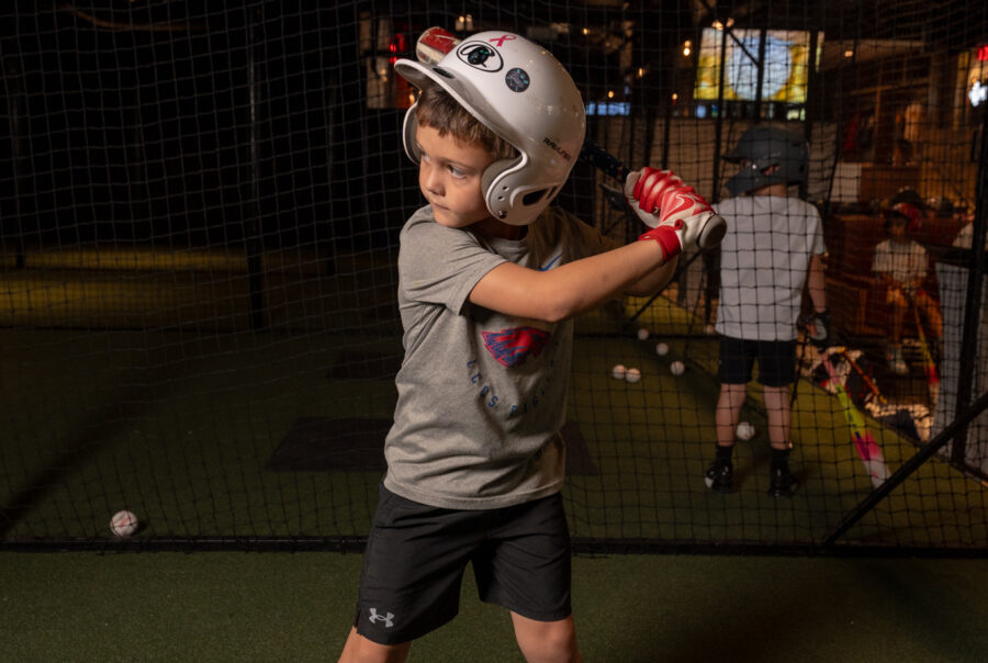 Guest taking a swing on an indoor batting simulator at Batbox Dallas sports entertainment venue